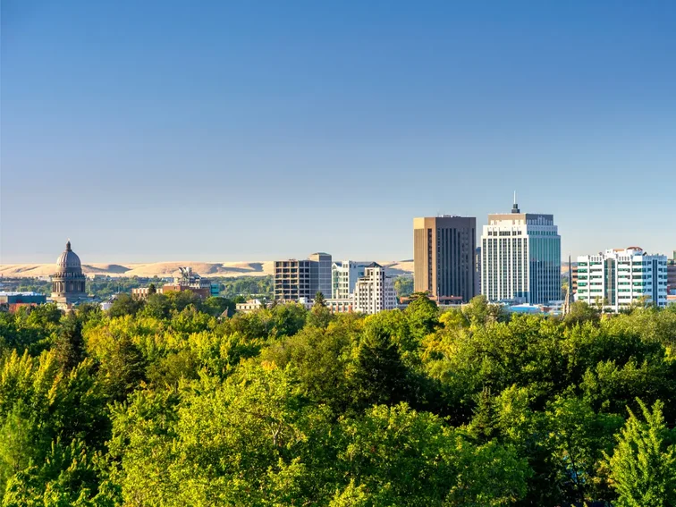 Scenic view of downtown Boise, Idaho with lush green trees under a clear blue sky.